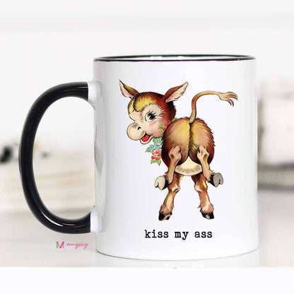A white ceramic coffee mug with a black rim and handle, featuring a double-sided print of a donkey with a flower in its mouth and the phrase 'KISS MY ASS' on the other side.